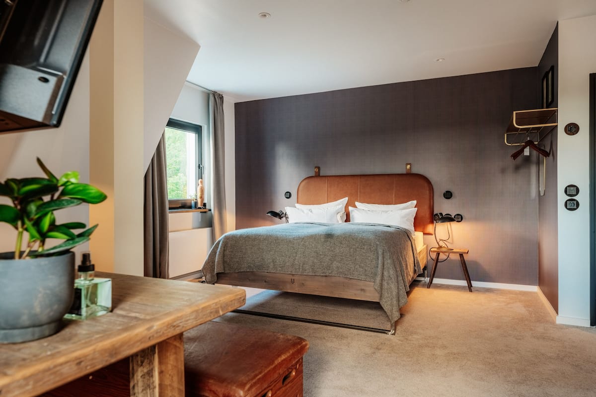 A modern bedroom with a bed, bedside table, and a potted plant.
