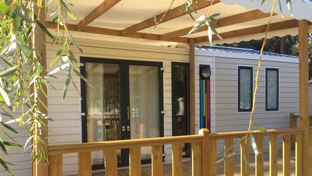A wooden deck with a glass door leading to a white mobile home. - Camping Milella (Olmeto)