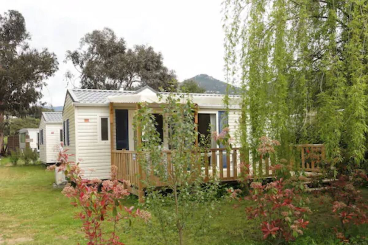Una casa móvil con terraza y un pequeño jardín.