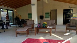 A spacious indoor area with wooden furniture, a red patterned rug, and a sign indicating a special offer. - Camping Milella (Olmeto)