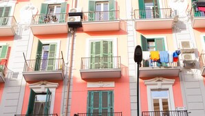 A multi-story building with balconies, green shutters, and a visible storefront with a sign. - B&B Sosta Flegrea (Naples)