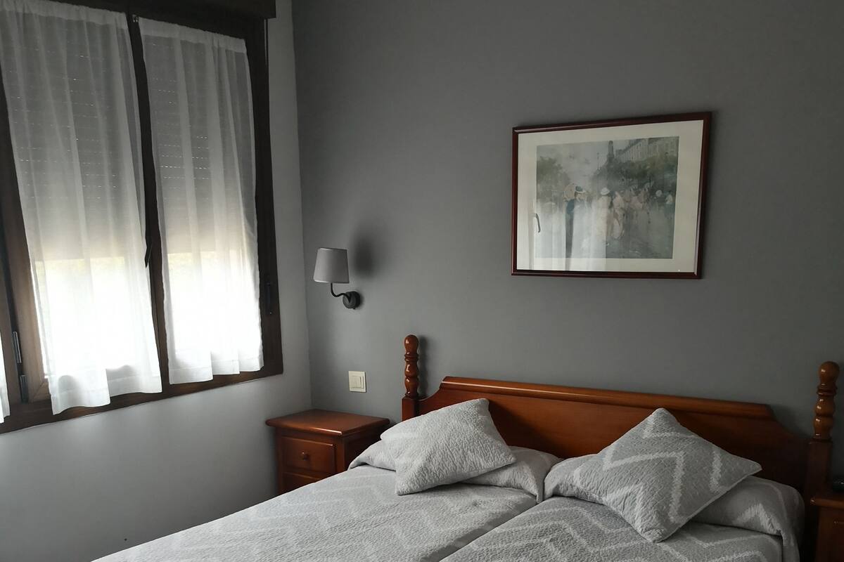 Un dormitorio con dos camas, una mesita de noche, una lámpara de pared y un cuadro en la pared.