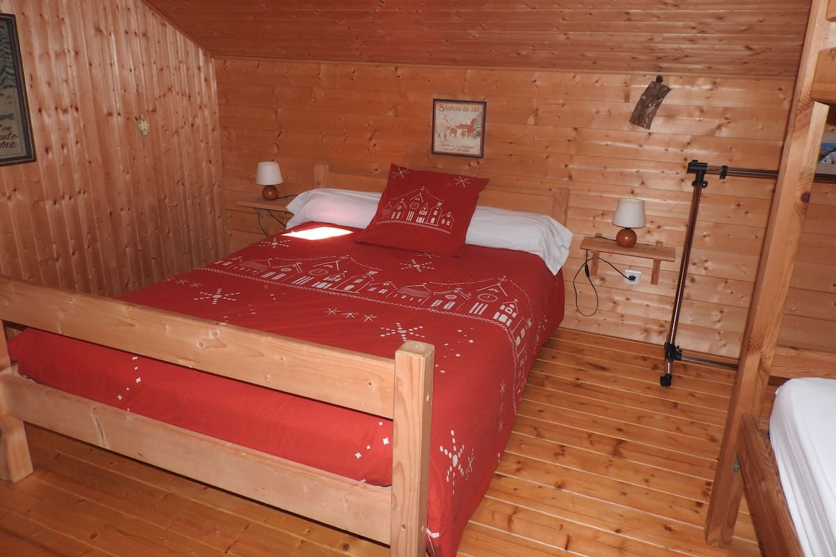 Een houten kamer met een bed, twee nachtkastjes en een wandlamp.