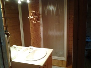 Een houten badkamer met een witte wastafel en een spiegel.
