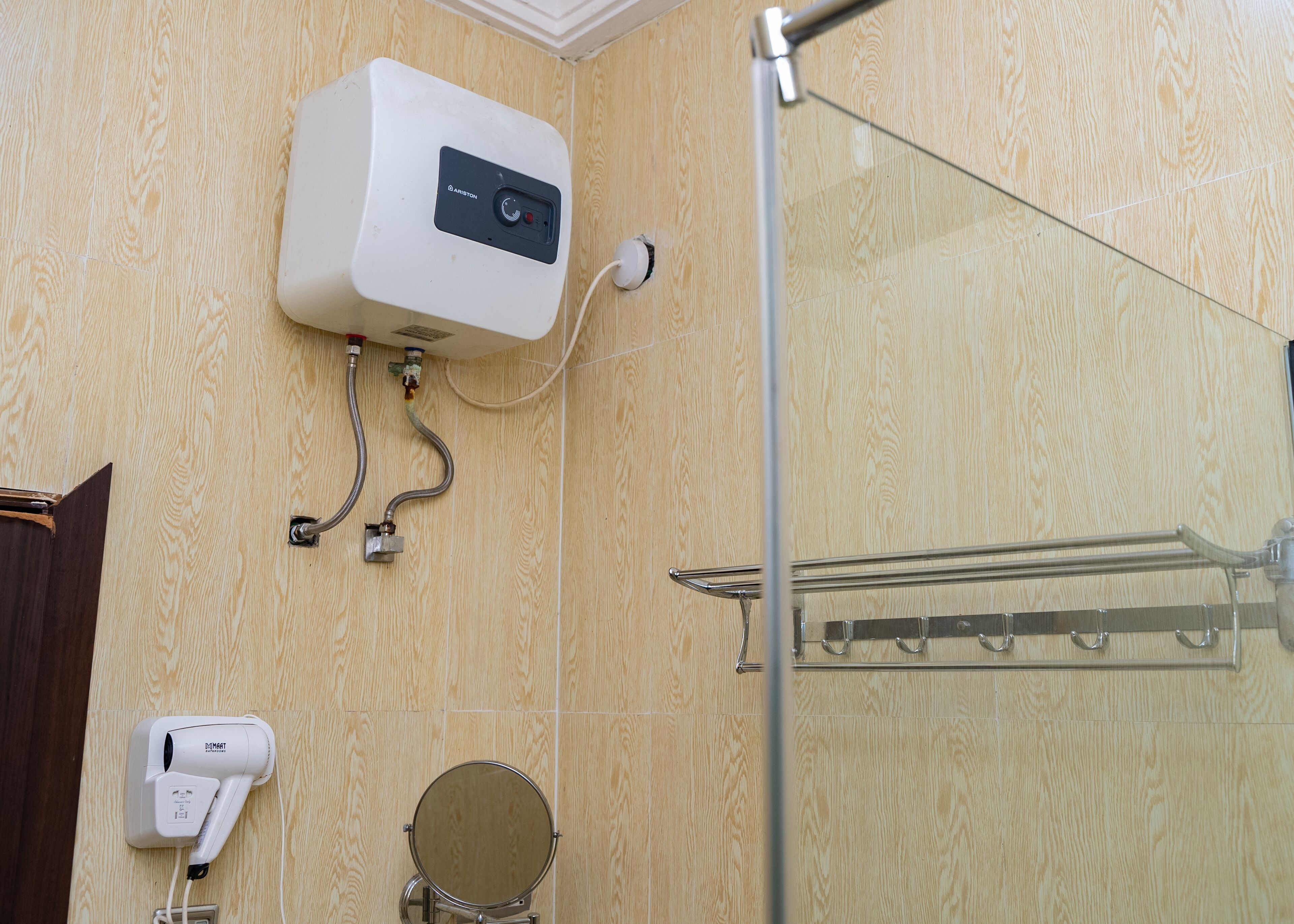 A bathroom with a shower, a toilet, and a hairdryer on the wall.