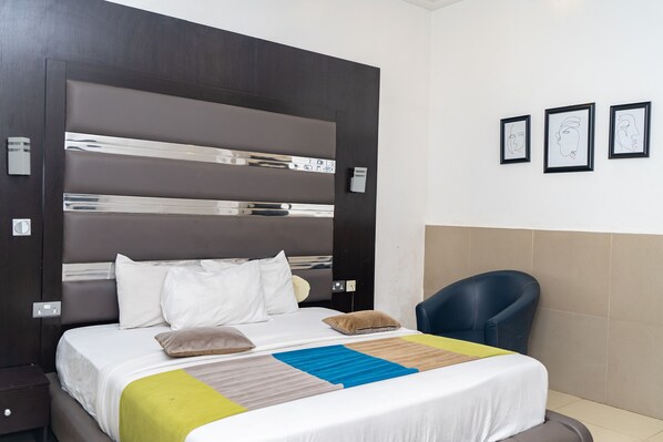 Habitación de hotel con una cama grande, una silla y tres obras de arte enmarcadas en la pared.