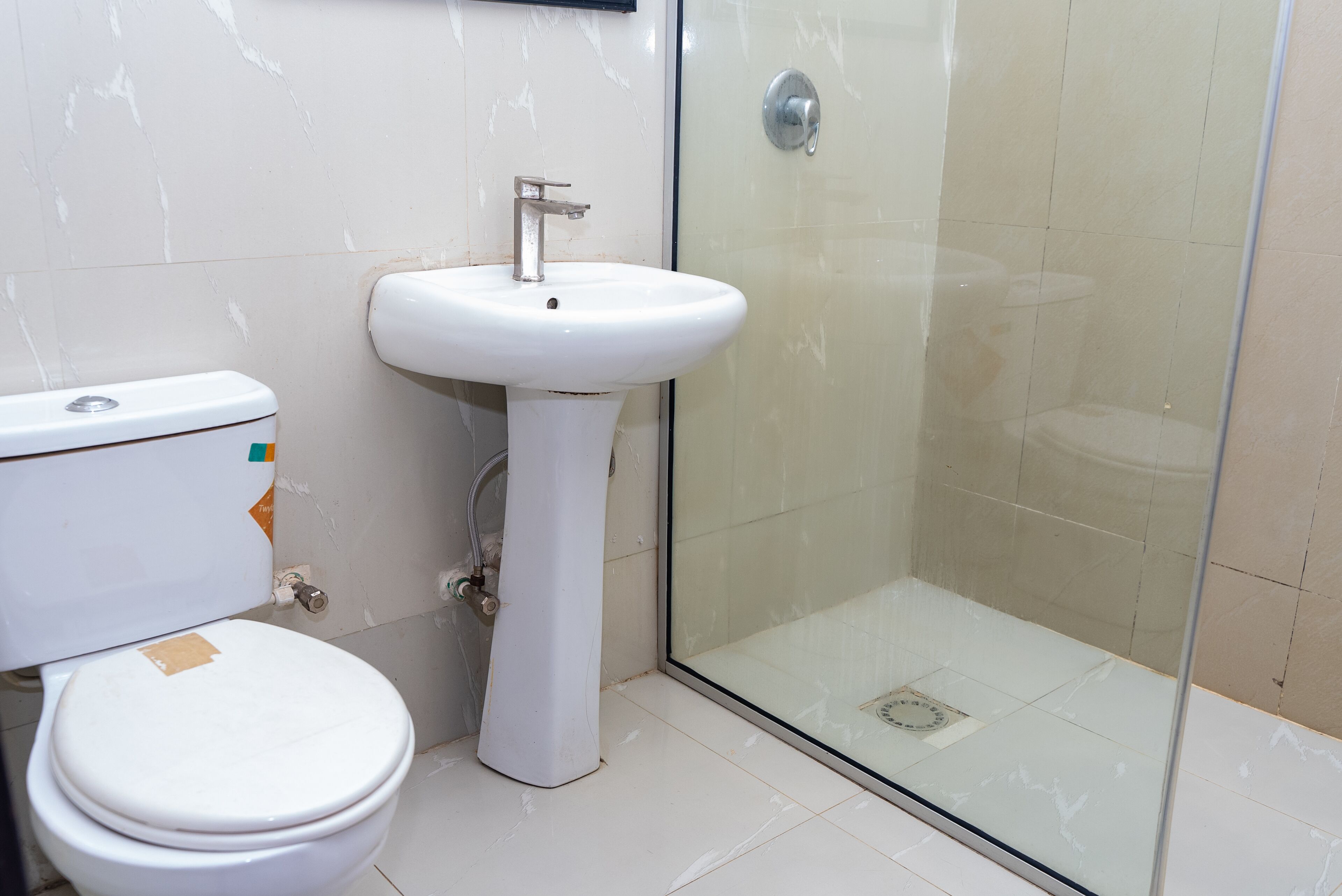 A bathroom with a toilet, sink, and glass shower enclosure.
