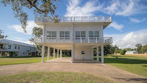 A two-story building with a balcony on the upper floor, a covered entrance, and a grassy yard.