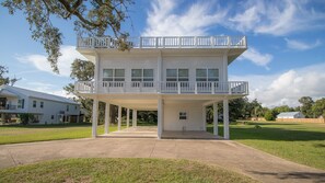 A two-story building with a balcony on the upper floor, a covered entrance, and a grassy yard. - Breathtaking Beach Front Home With Significant Vacation Specials! Sleeps 8!!! (Long Beach)