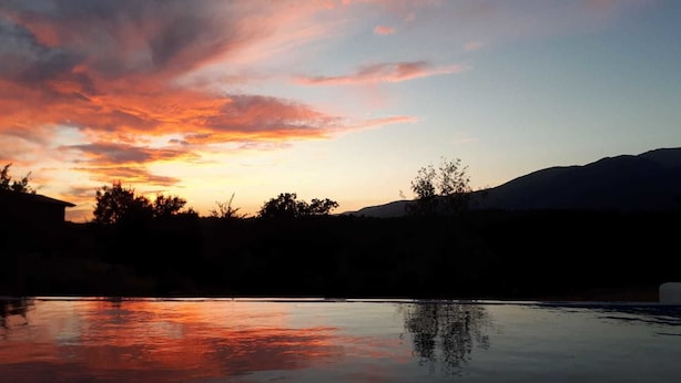 A serene sunset over a calm lake with silhouettes of trees and distant mountains. - Sakura Vera (Villanueva De La Vera)