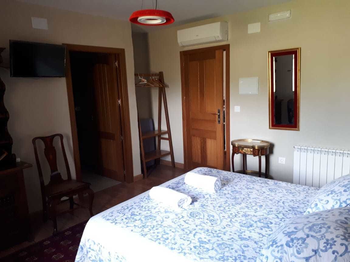 Une chambre d’hôtel avec un lit, une chaise, une petite table, un miroir et un téléviseur.