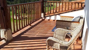 A covered terrace with terracotta tiles, wicker furniture, and a wooden railing overlooking a scenic landscape. - Sakura Vera (Villanueva De La Vera)