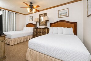 Habitación de hotel con dos camas, un ventilador de techo, un aparador y un televisor.
