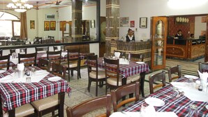 Un restaurante con varias mesas dispuestas para comer, una zona de bar y un mostrador de recepción.