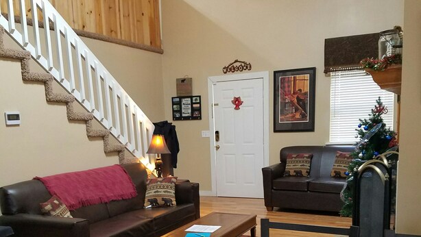 A living room with a staircase, two sofas, a coffee table, and a Christmas tree.