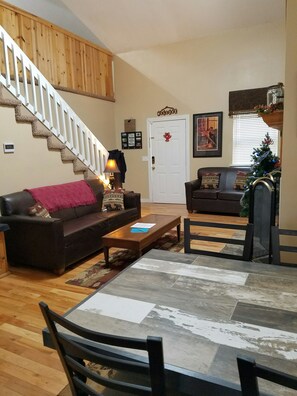 Relax in this inviting living space with a cozy sofa, wooden staircase, and comfortable dining area.