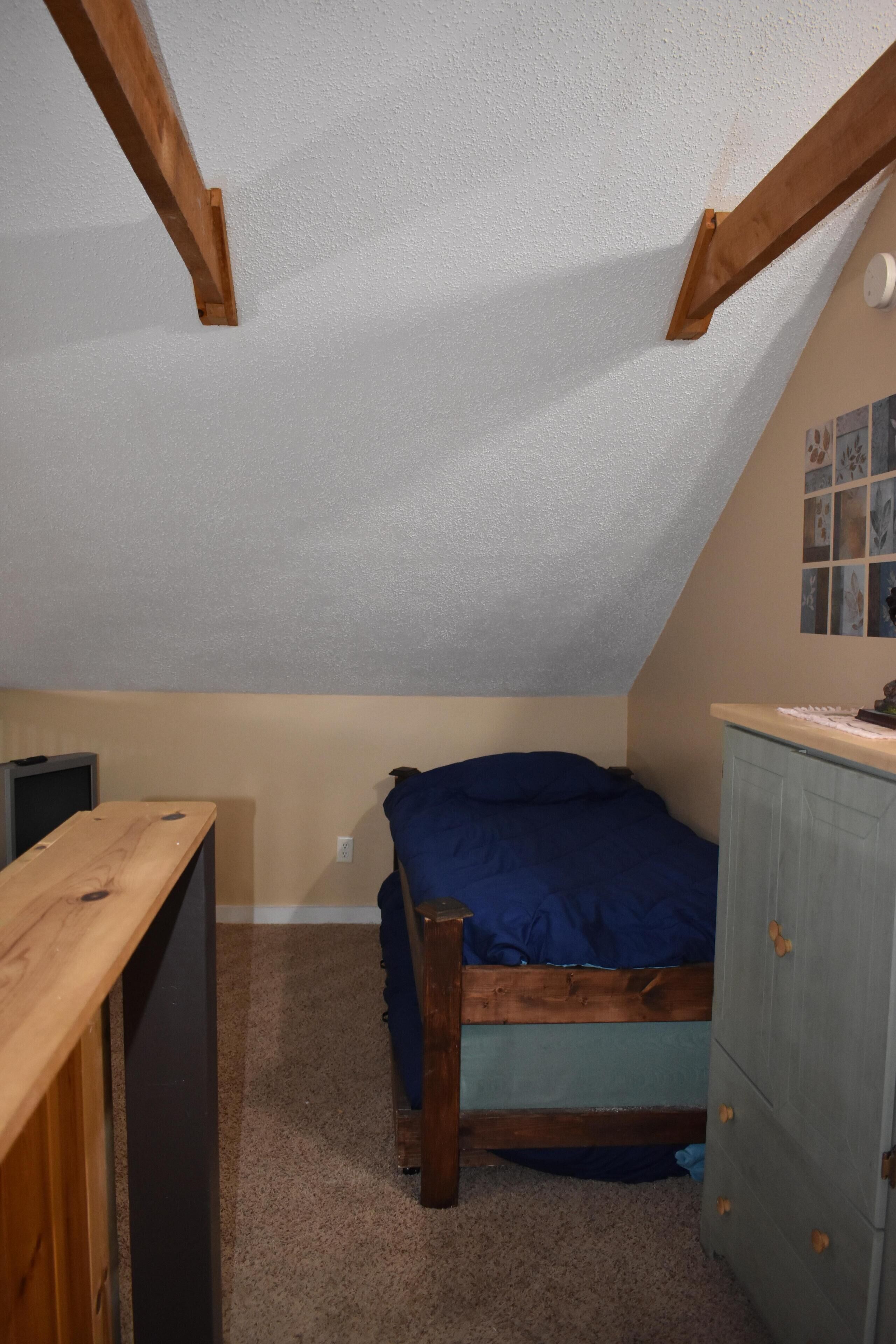 Een slaapkamer met een stapelbed, een bureau, een dressoir en een plafondventilator.