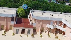 A multi-story building with a central courtyard, balconies, and a red roof. - Residence Club Azzurro (Massignano)