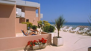 A poolside area with lounge chairs and a palm tree. - Residence Club Azzurro (Massignano)