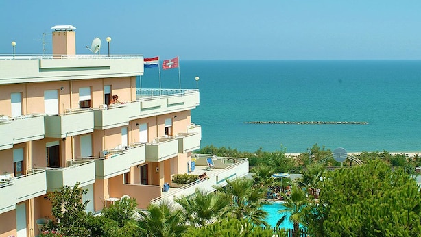 A multi-story hotel with balconies overlooking a beach and the sea. - Residence Club Azzurro (Massignano)