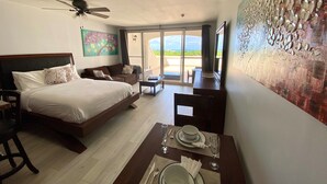 Camera d'albergo con un letto, una scrivania con tavola imbandita, una ventola a soffitto e vista sull'esterno.