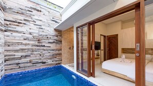 Ein modernes Hotelzimmer mit einer großen Schiebeglastür, die auf einen Balkon mit einem Pool führt.