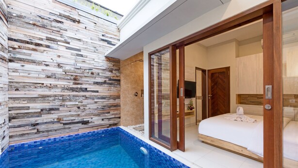 A modern hotel room with a large sliding glass door leading to a balcony with a pool. - Paisa Seminyak Living (Keroboken Kelod)