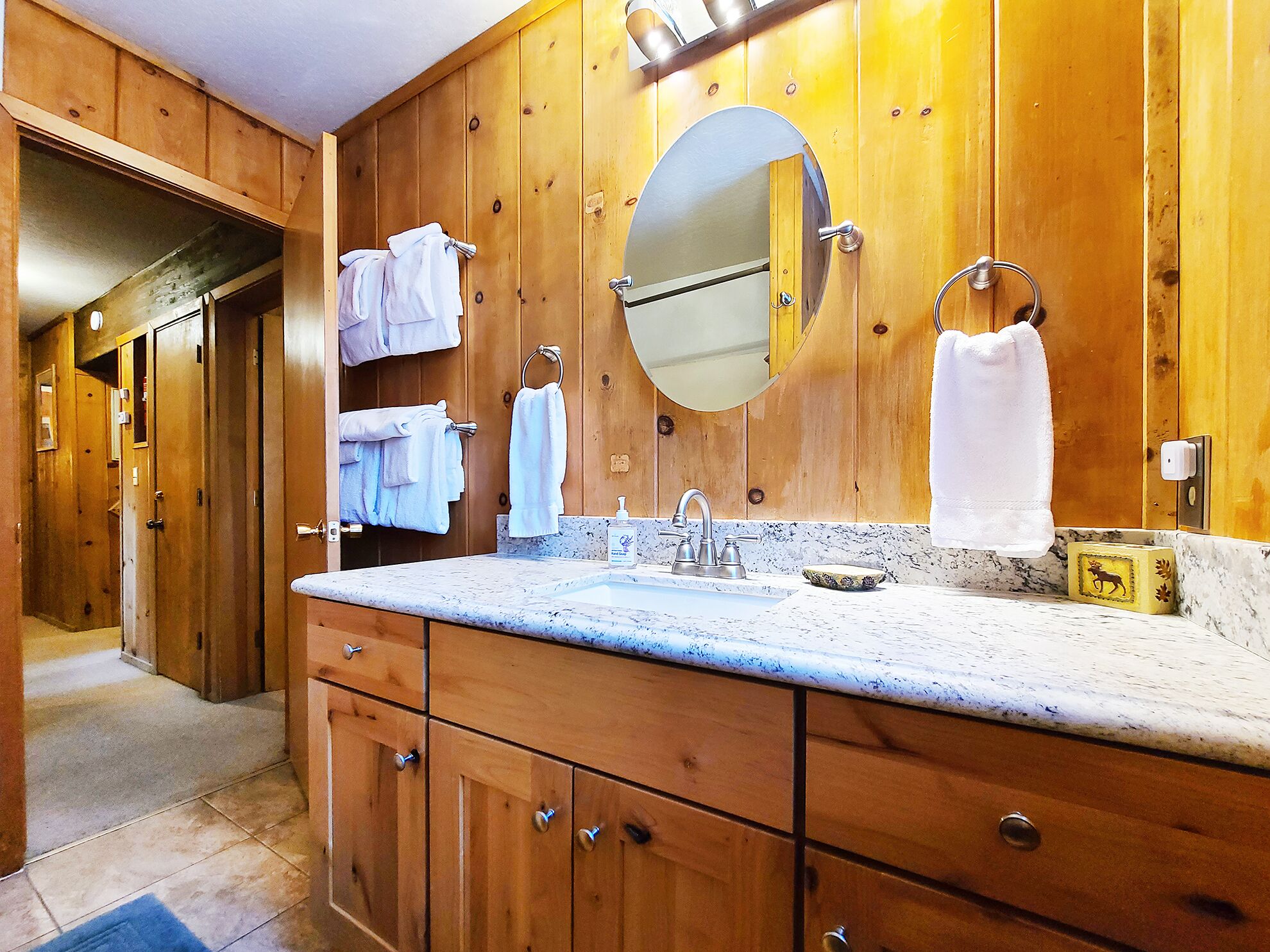 A wooden bathroom with a sink, mirror, and towel rack.