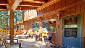A wooden cabin with a covered porch, outdoor seating, and large windows.