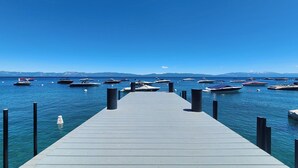 A pier leading into a calm body of water with several boats docked at the end.