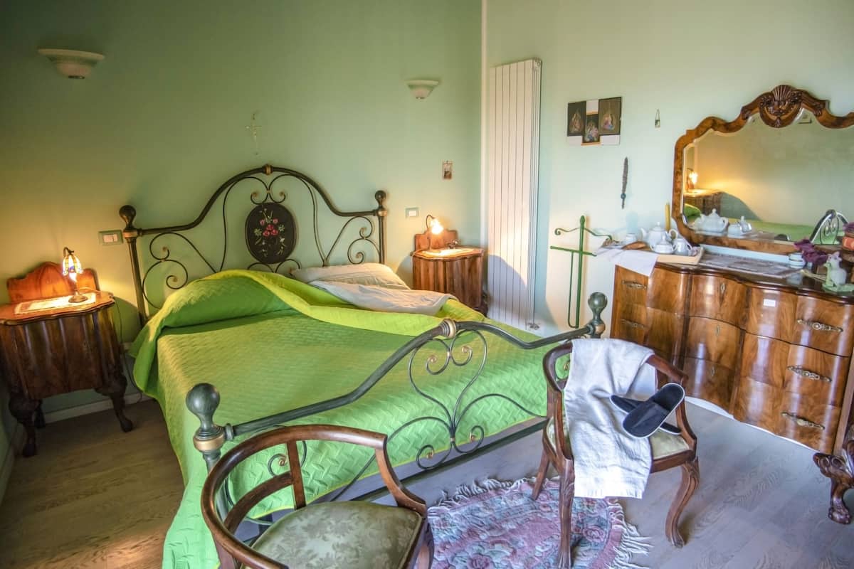 A bedroom with a bed, a chair, a dresser, and a mirror.
