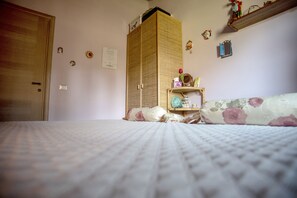 A bedroom with a bed, a wardrobe, a shelf with decorative items, and a door. - Villa Farfalla Bianca (Vitorchiano)