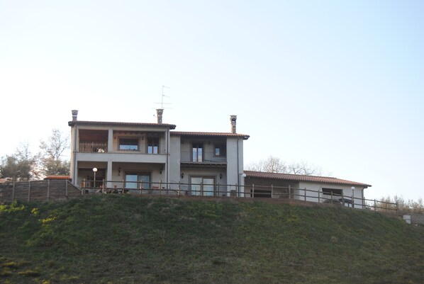 A two-story house with a balcony on the upper floor, situated on a hillside. - Villa Farfalla Bianca (Vitorchiano)