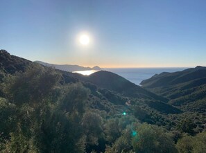 A mountainous landscape with a clear sky and a body of water in the distance. - Les Asphodèles (Partinello)