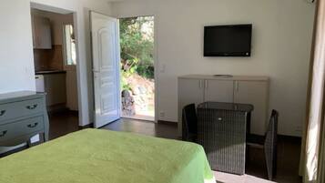 A bedroom with a bed, a television, a desk, and a view of the outdoors.