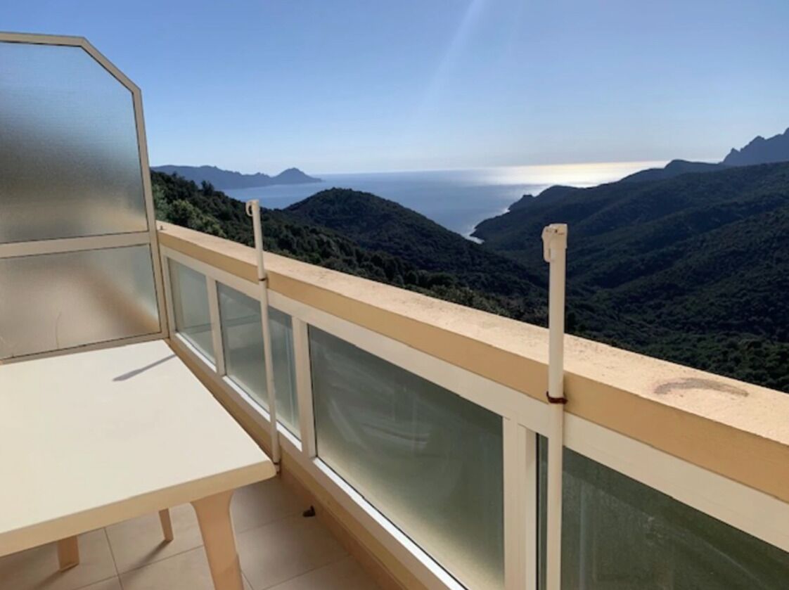 Un balcone con vista panoramica su un paesaggio montuoso e il mare.