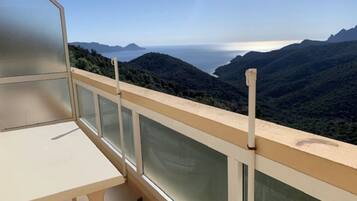 Un balcone con vista panoramica su un paesaggio montuoso e il mare.