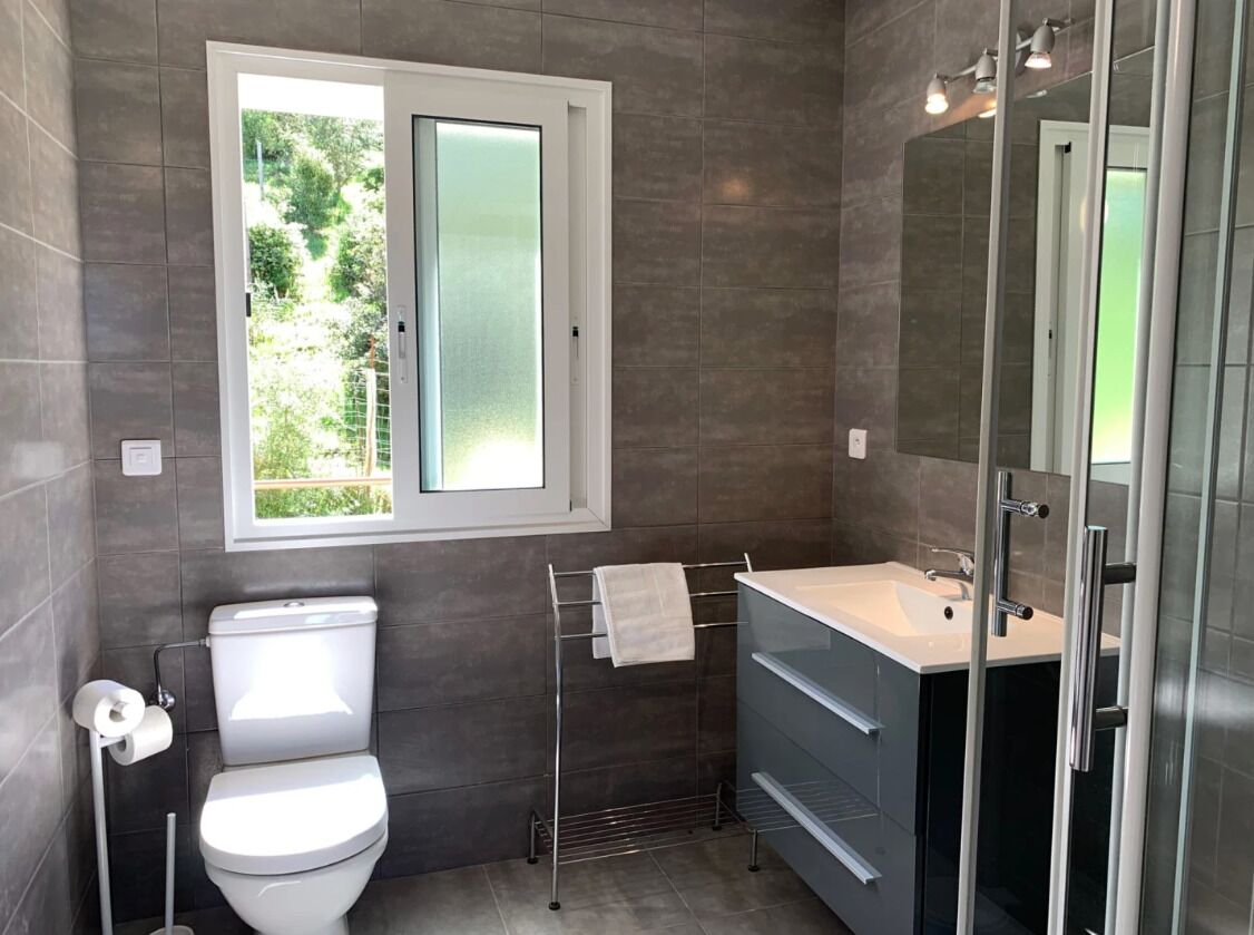 A modern bathroom with a toilet, sink, and shower.