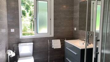 A modern bathroom with a toilet, sink, and shower.