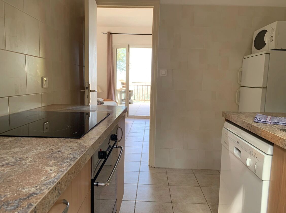 A kitchen with a built-in stove, oven, and dishwasher, a granite countertop, and a view to a balcony.