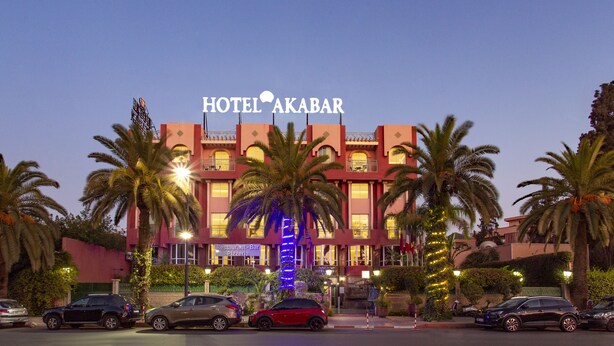 Un hotel con un letrero llamativo que dice "HOTEL AKABAR" y un restaurante-bar llamado "Pizzeria" en la planta baja.