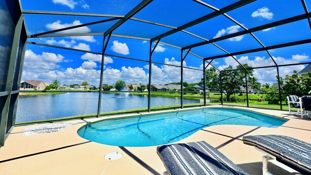 Piscina cubierta al aire libre con vista a un lago y casas al fondo.