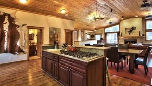 A spacious kitchen with a large island, wooden ceiling, and a fireplace. - Beautiful 6 Bedroom, 4 Bathroom Home Centrally Located and Perfectly Appointed (South Lake Tahoe)