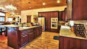 A spacious kitchen with wooden cabinets, a large island, and built-in appliances. - Beautiful 6 Bedroom, 4 Bathroom Home Centrally Located and Perfectly Appointed (South Lake Tahoe)