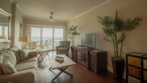 A living room with a sofa, coffee table, TV, and decorative plants.
