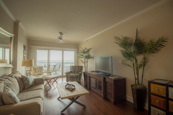 A living room with a sofa, coffee table, TV, and decorative plants.