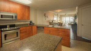 A modern kitchen with granite countertops, stainless steel appliances, wooden cabinets, and a central island.