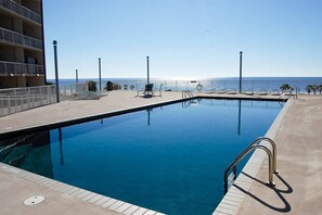 A swimming pool with a clear view of the ocean, surrounded by lounge chairs and a building with balconies. - I'll Have A Side Of Beach With My Morning Coffee! Directly On The Sand!!! (Biloxi)