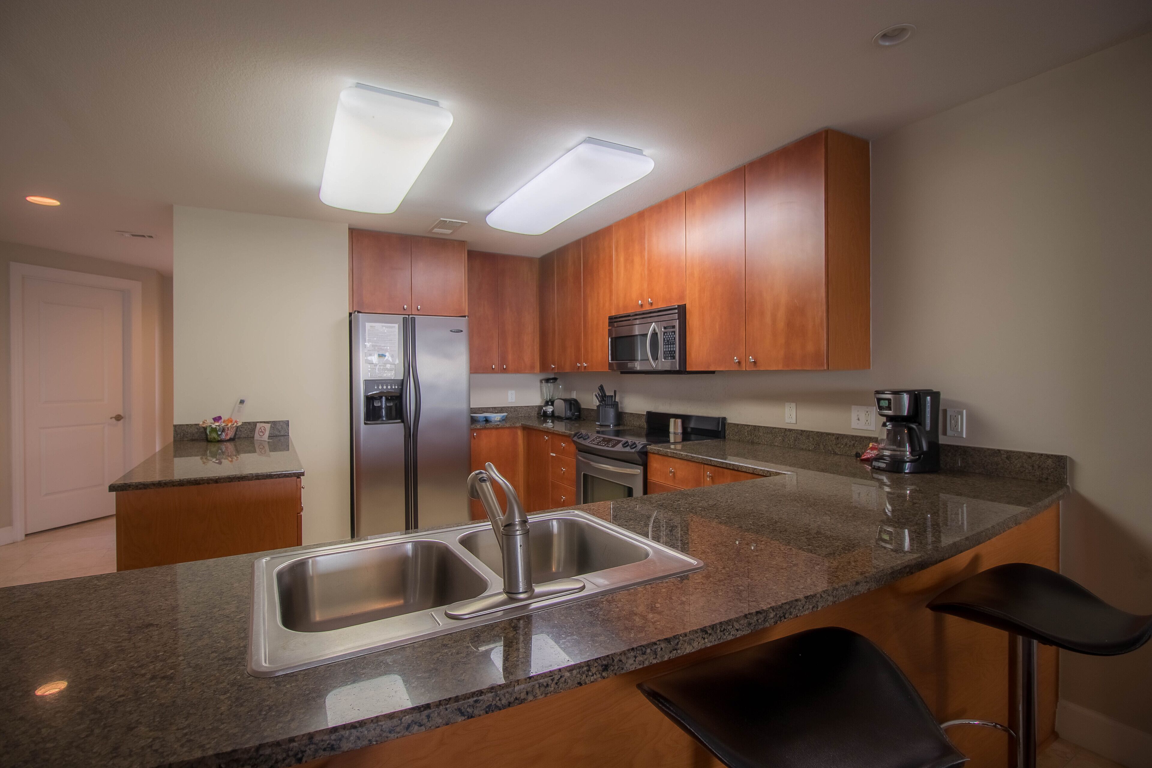 A modern kitchen with granite countertops, stainless steel appliances, and wooden cabinets.