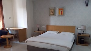 A hotel room with a bed, bedside tables, a desk, and a chair.
